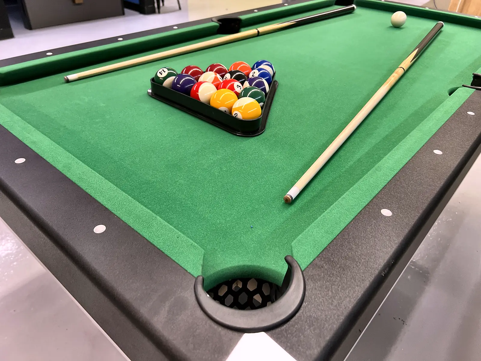 Racked balls and cues on green felt